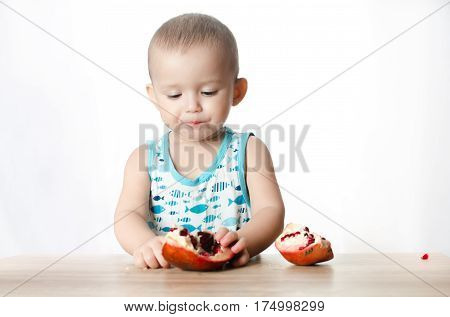 Baby eats a pomegranate ripe and juicy very tasty and joyfully