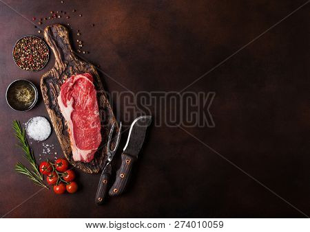 Raw Sirloin Beef Steak On Old Vintage Chopping Board With Knife And Fork On Rusty Background. Salt A
