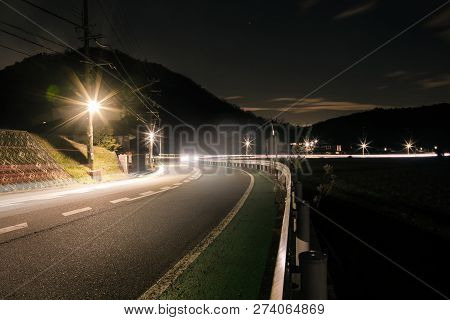 Streetlights Create Starbursts Alongside Deserted Country Road At Night