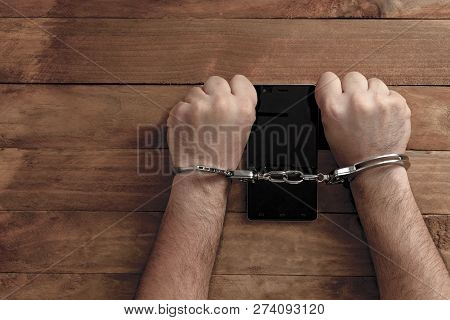 Crime Concept In The Network. Shaking Hands Holding A Mobile Phone.