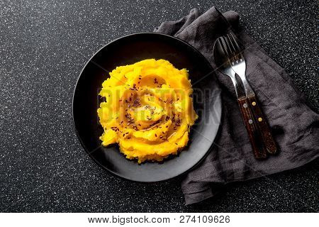 Mashed Potato With Pumpkin In Black Bowl. Dark Background. Top View