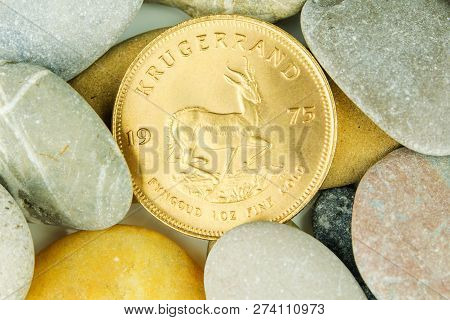 Golden Ounce Of Krugerrand Coin Hidden Under Pebble Stones