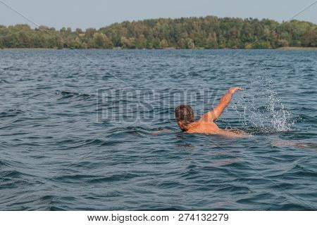 Young Man Is Swimming Fast In The Lake On A Sunny And Warm Day
