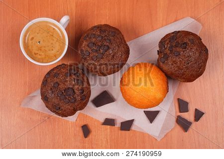 White Porcelain Cup Of Coffee, Tasty Chololate And Vanilla Muffins And Pieces Of Black Chocolate On 