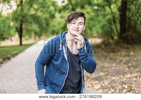 Portrait Of Attractive Young Caucasian Man With Dark Curly Hair Touches His Chin, Smiling. Golden Ro