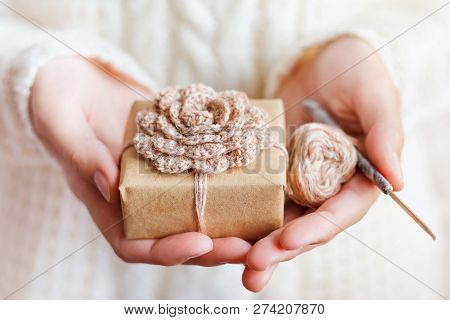 Woman In White Knitted Sweater Holding A Present Wrapped In Craf