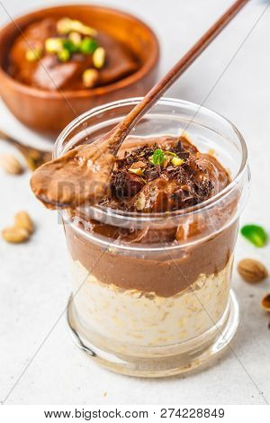 Overnight Oatmeal With Milk And Chocolate Mousse In A Glass On A White Background.