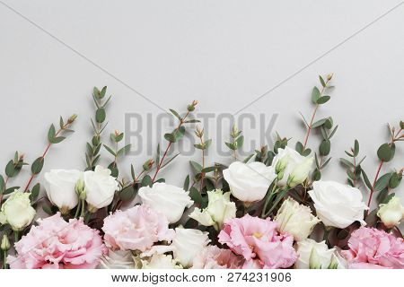 Beautiful Floral Border Of Pastel Flowers And Green Eucalyptus Leaves On Gray Table Top View. Flat L