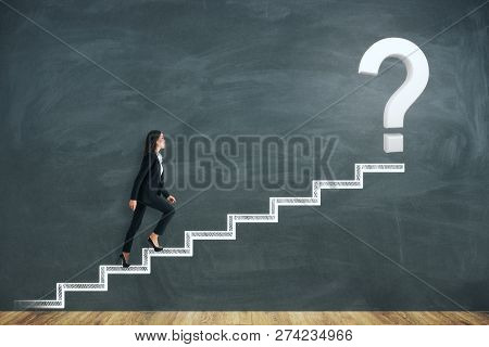Side View Of Young Businesswoman Climbing Abstract Drawn Stairs With Question Mark On Chalkboard Bac