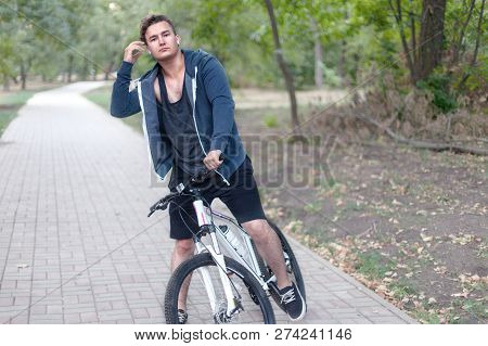 Attractive Young Caucasian Man With Dark Hair Bicycling In The Park. Outdoors, Autumn / Fall Park. D
