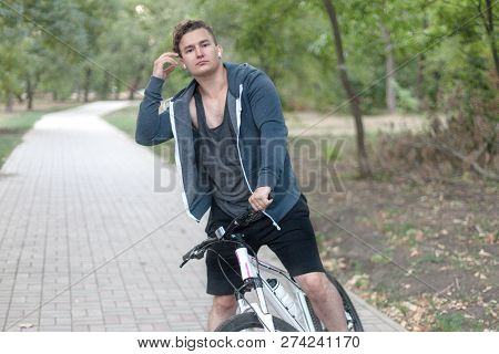 Attractive Young Caucasian Man With Dark Hair Bicycling In The Park. Outdoors, Autumn / Fall Park. D