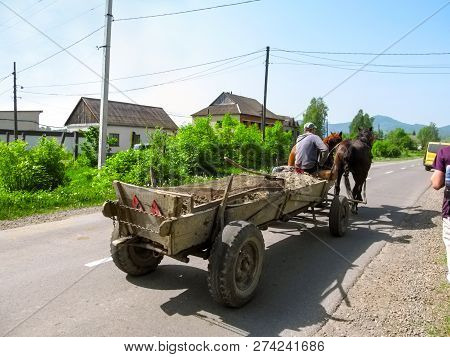 Ukraine, Khust - May 1, 2018: A Cart Pulled By Two Horses Rides On A Paved Rural Road In Khust. Simp