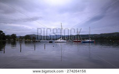 A View Across Ullswater With Boats Moored Up In The Lake District