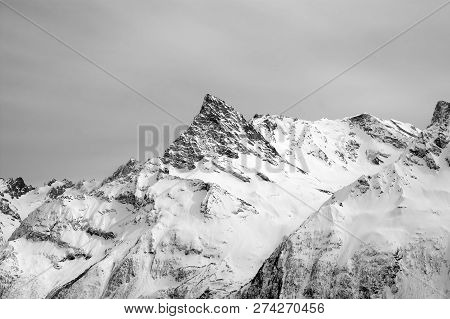 Black And White Snowy Mountains And Grey Cloudy Sky. Caucasus Mountains In Winter, Region Dombay, Mo