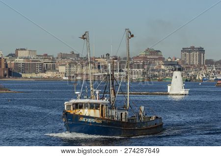 New Bedford, Massachusetts, USA - December 11, 2018: Commercial fishing vessel Silverfox, hailing port Cape May, New Jersey, under way with Palmer Island Light Station in background