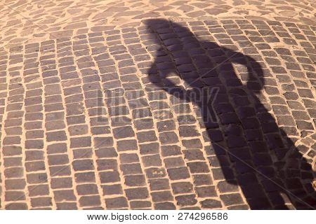 Strange Shadow Of A Woman On An Old Stone Road. Black Shadow, Female Hand. Background, Texture, Crop