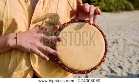 Man Playing On A Drum With His Hands, Close Up. Hands Tapping A Small Drum