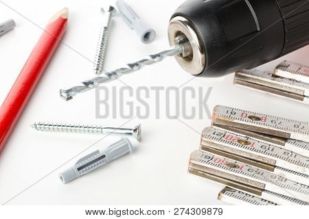 Wall Plug Dowel With Screw, Electric Power Drill, Folding Rule And Pencil On White Table - Home Impr