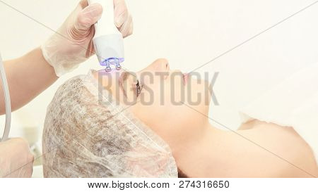 Facial Micro Current Cosmetology Procedure. Beauty Technology Treatment. Woman Face Therapy.