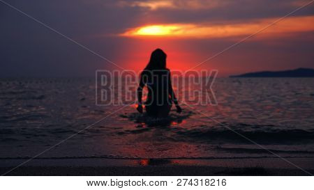 Silhouette Of A Woman Emerging From The Sea Against The Backdrop Of The Sea Landscape, A Red Dramati
