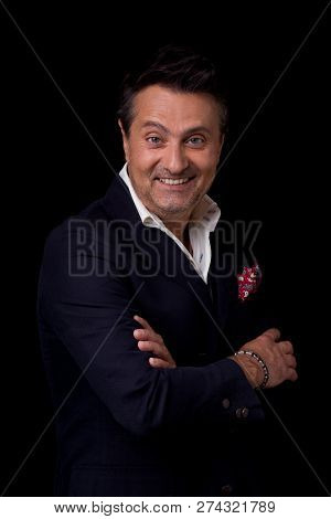 Laconic Portrait Of The Emotional Frenchman Smiling While Standing With His Arms Crossed Against The