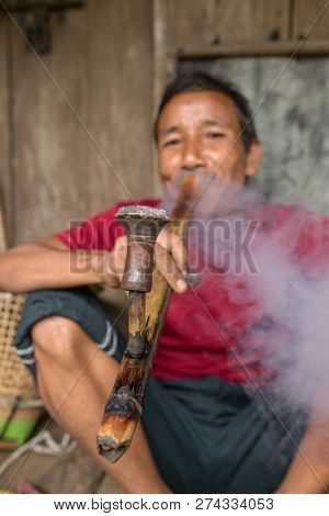 Meghalaya, India - May 15, 2017: Khasi man smoking traditional long pipe with tobacco