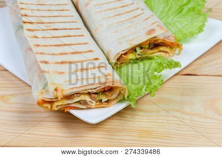 Fragment Of Two Portion Of Shawarma Wrapped Inside Of A Flatbread And Grilled, Lettuce Leaves On A D