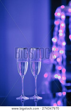 Holiday Pair Of Glasses Of Champagne In The Interior. Blurred Luminocity Neon Color Backdround. Chri
