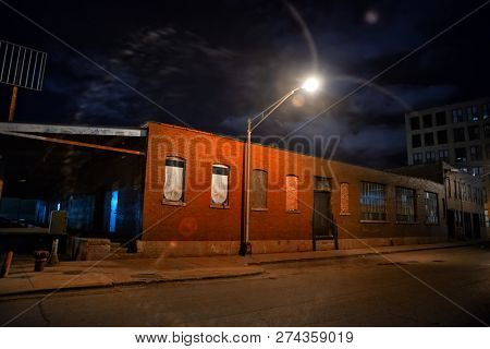 Scary industrial urban street city night scene with a decaying loading dock by a vintage factory warehouse
