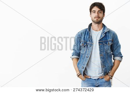 Stylish And Cofnident Handsome Young Man With Beard And Blue Eyes Holding Hands In Pockets As Standi