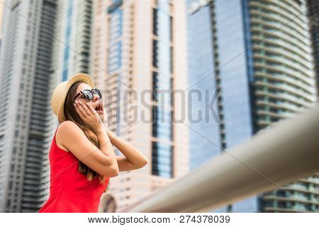 Portrait Of Young Pretty Woman In Red Dress, Sunglasses And Straw Hat Amazed Of The View On Downtown