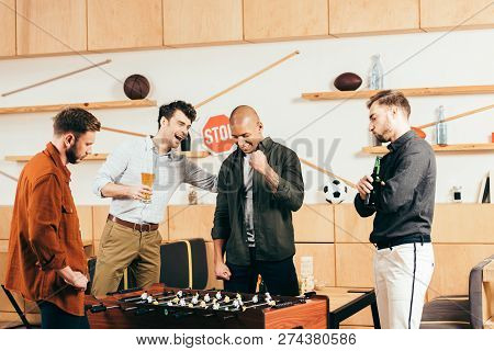 Multiracial Young Friends Playing Table Football Together In Cafe