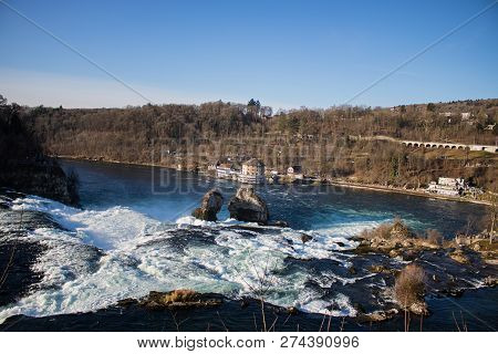 View On Two Big Stones On The Lower Part Of Rhine Waterfall On The Background Of Fotest, Canton Scha