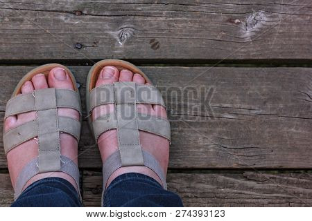 Womens White Feet Standing In Sandles On Old Wooden Boards