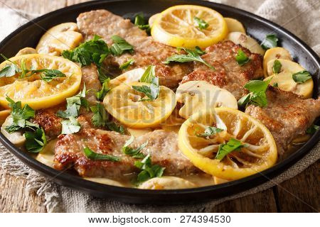 Tasty Italian Fillet Of Veal Scaloppini With Mushrooms And Lemons In Sauce Close-up In A Frying Pan.
