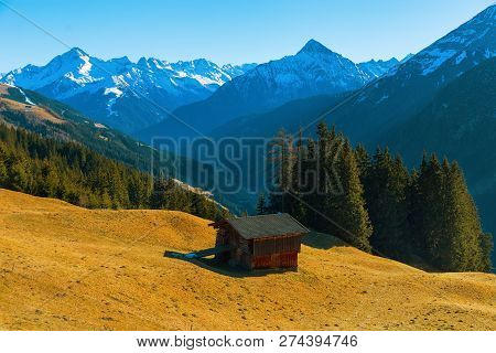Mountain Landscape. Beautiful Landscape. Austrian Alps. A Small House On The Hillside Against The Ba