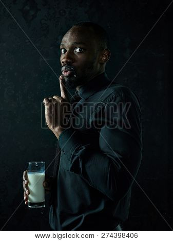Healthy Young African Man Holging Cup Of Milk On A Bllack Studio Background.