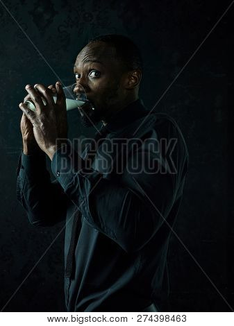 Healthy Young African Man Holging Cup Of Milk On A Bllack Studio Background.