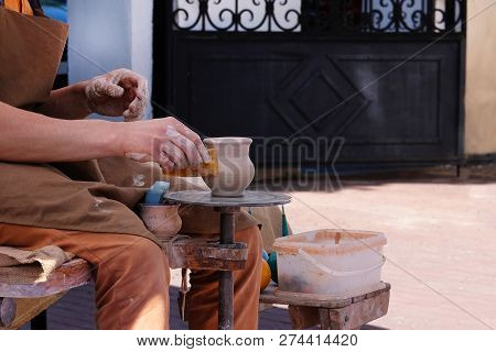 Hands Of A Potter, Creating An Earthen Jar On Potters Wheel. Pottery And Craftsmanship Concept.
