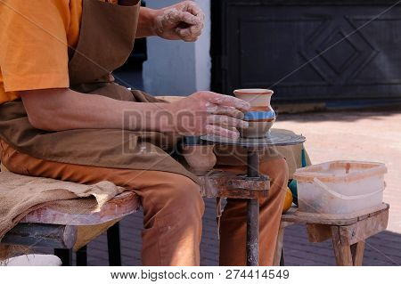 Hands Of A Potter Makes A Clay Pot On Potters Wheel. Pottery And Craftsmanship Concept.