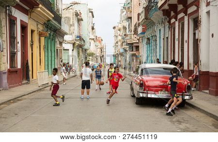 HAVANA-CUBA- DEC 5, 2018: Kids playing ball in the street in Centro Habana, one of the 15 municipalities or boroughs in the city of Havana, Cuba.