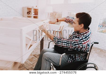 Young Man On Wheelchair Assembling Wooden Bookshelf At Home. Wooden Bookcase. Selfmade Furniture. Wh
