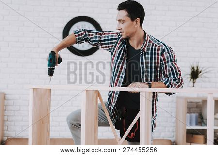 Young Man Assembling Wooden Bookshelf At Home. Wooden Bookcase. Selfmade Furniture. Man And Hobby. W