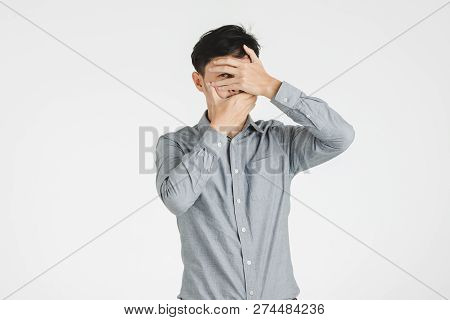 Young Asian Man Portrait Covering Mouth And Eye By His Hands As Secret Or Silence Sigh, Isolated On 