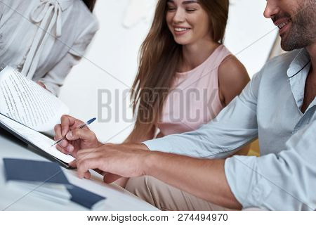 Young Lovely Couple Sitting With Manager At The Travel Agency Office And Signing Contract For A Vaca
