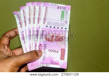 Selective Focus: Hand Holding Indian 2000 Rupee Notes Against Isolated Background. Close Up Of The N