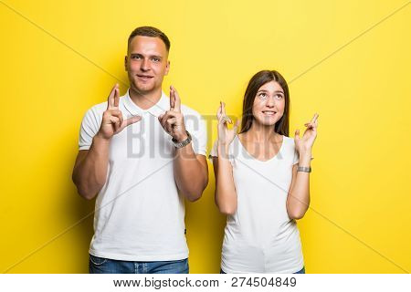 Young Female And Male Closing Thier Eyes Crossing Fingers With Hope While Anticipating Important New