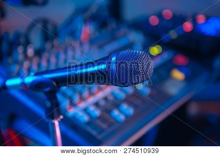 Microphone On The Blurred Background Of The Audio Mixer Of The Musician.