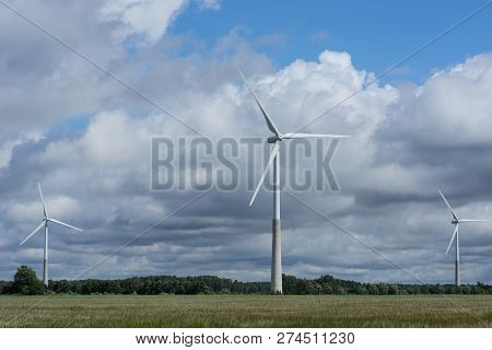 Ecology Concept: Blue Sky, White Clouds, Wind Turbine And Crop Field. Wind Generator For Electricity