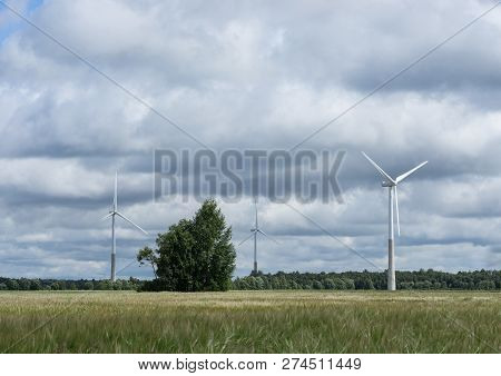 Ecology Concept: Blue Sky, White Clouds, Wind Turbine And Crop Field. Wind Generator For Electricity